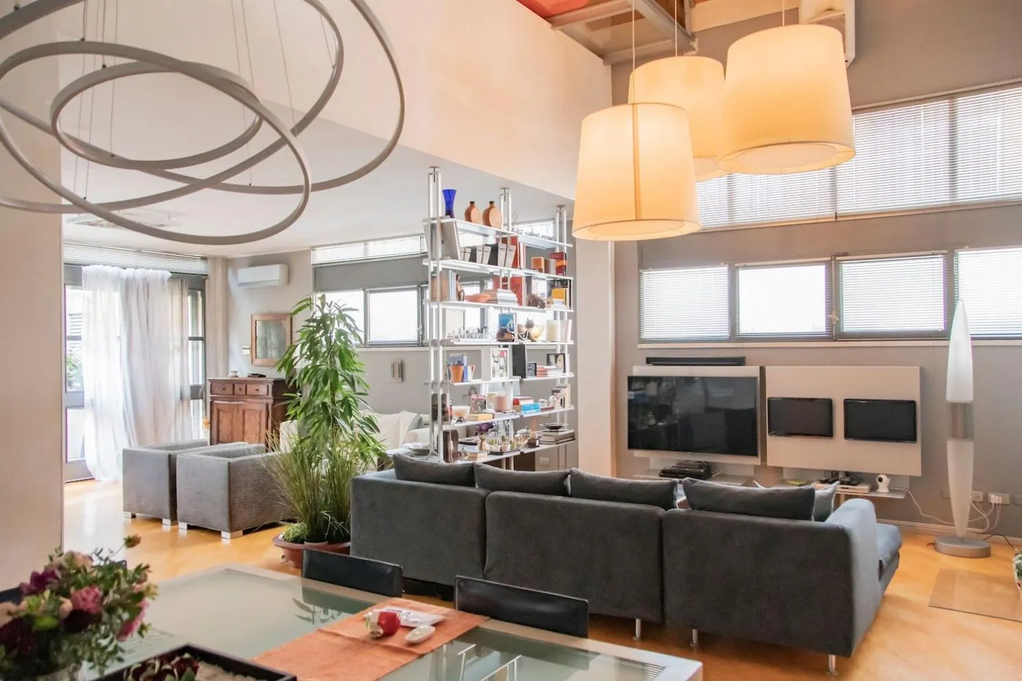 Sala della location con tavolo da pranzo, doppio soggiorno, illuminazione di design e pavimento in parquet