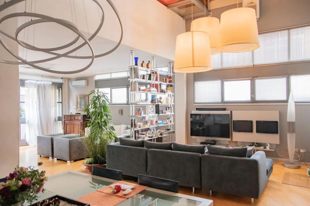 Sala della location con tavolo da pranzo, doppio soggiorno, illuminazione di design e pavimento in parquet