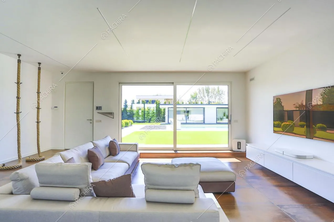 Salotto con corde pendenti dal soffitto, divano di design e ampie vetrate