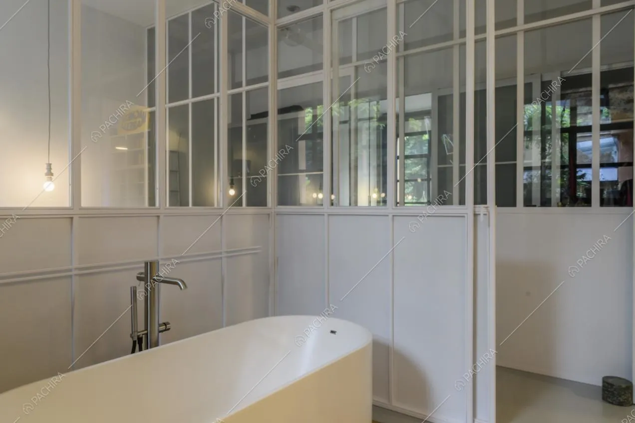 Vasca da bagno con vetrate industriali bianche e vista sul corridoio