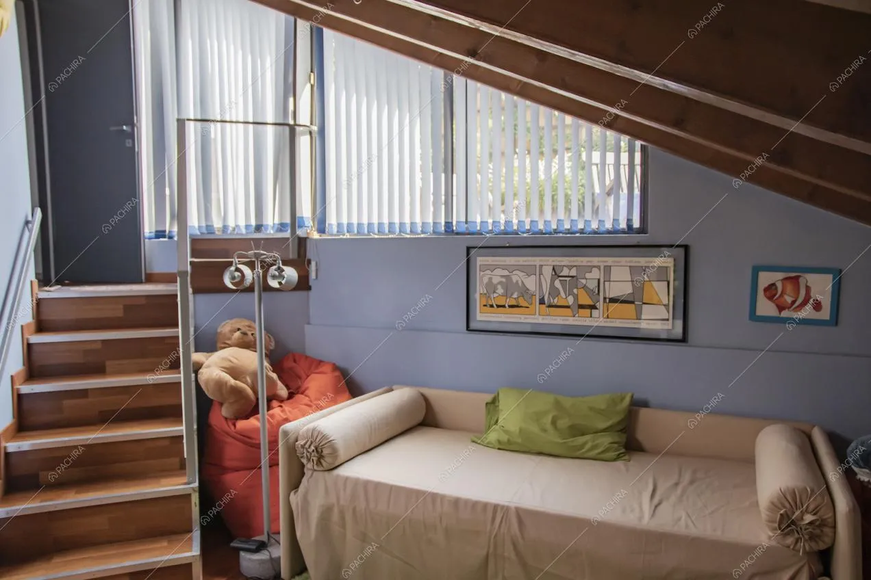 Nel solaio con il soffitto con travi in legno a vista, luminosa stanza da letto dalle pareti azzurre