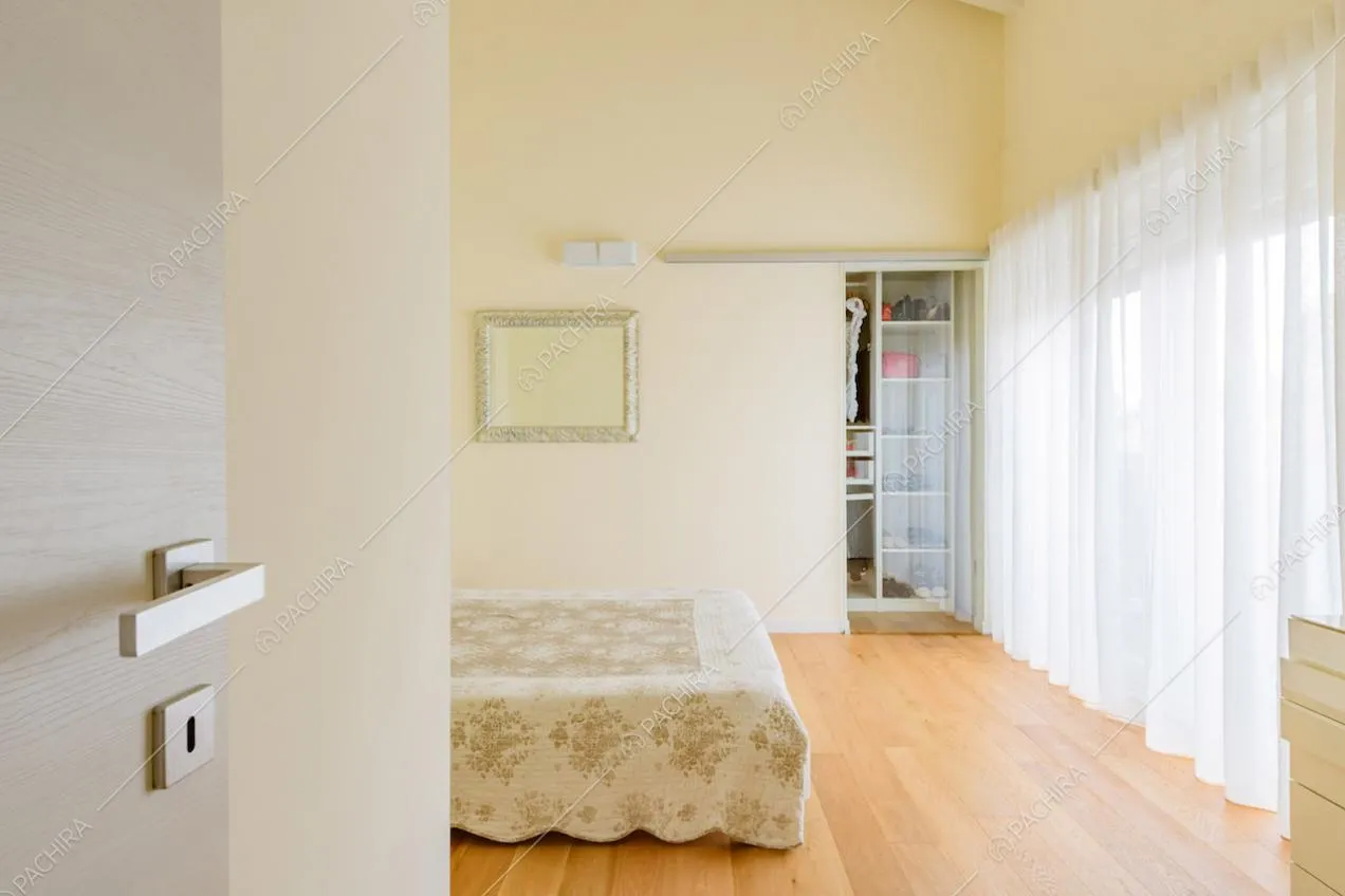 Pavimento in parquet, vetrate, pareti gialle e cabina armadio nella camera