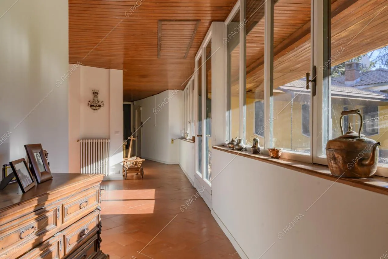 Corridoio con ampie vetrate, pavimento in cotto e soffitto con travi a vista in legno