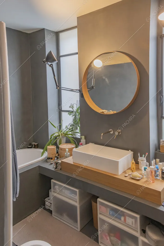 Specchio tondo, vasca e pareti scure nel bagno
