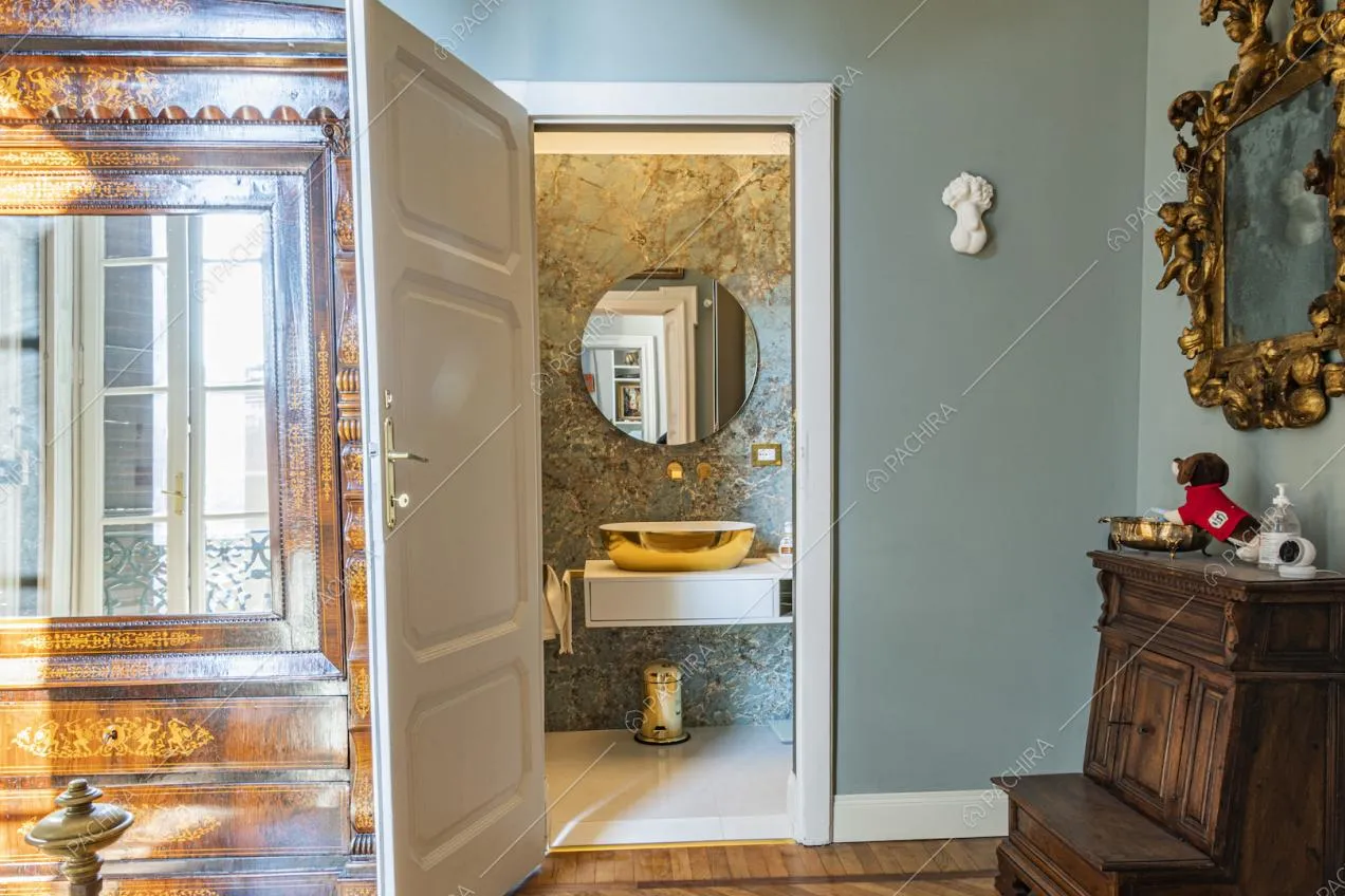 Specchio tondo e lavandino dorato nel bagno