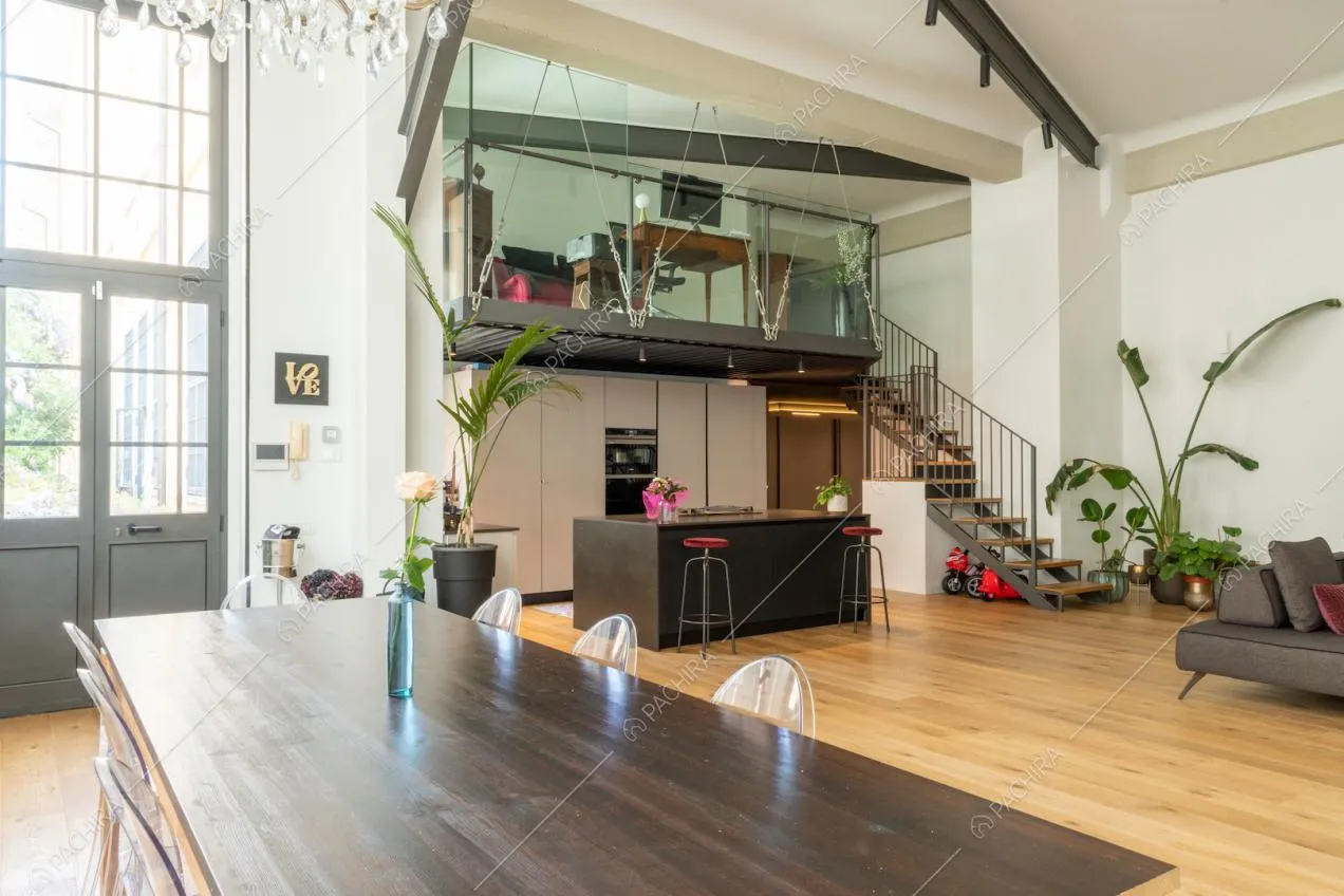 Tavolo da pranzo in legno con sedie di design, vetrate in stile industriale, cucina a vista con isola e soppalco