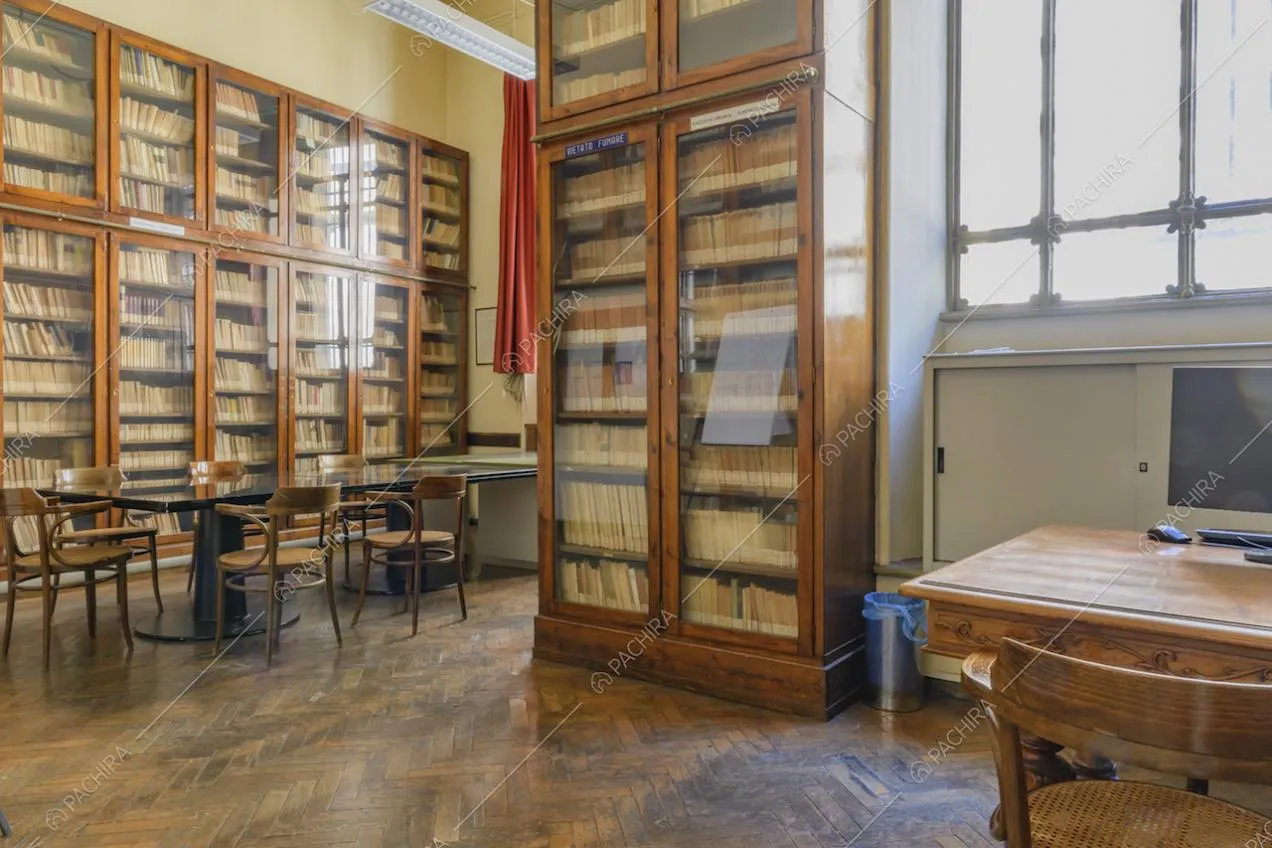 Biblioteca con antico pavimento in parquet a spina di pesce, tavoli e librerie a due livelli