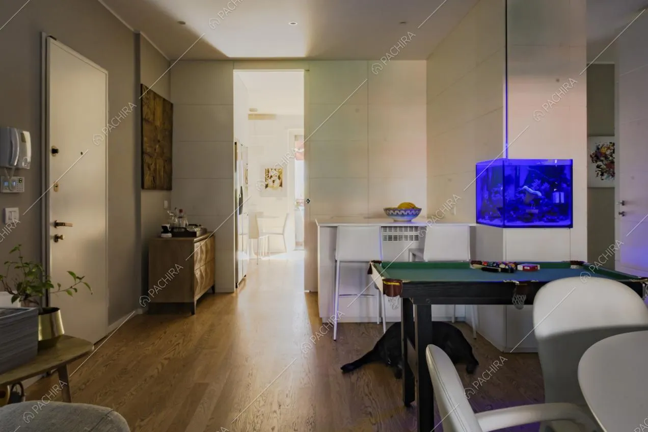 Pavimento in parquet, sgabelli alti e acquario all'ingresso