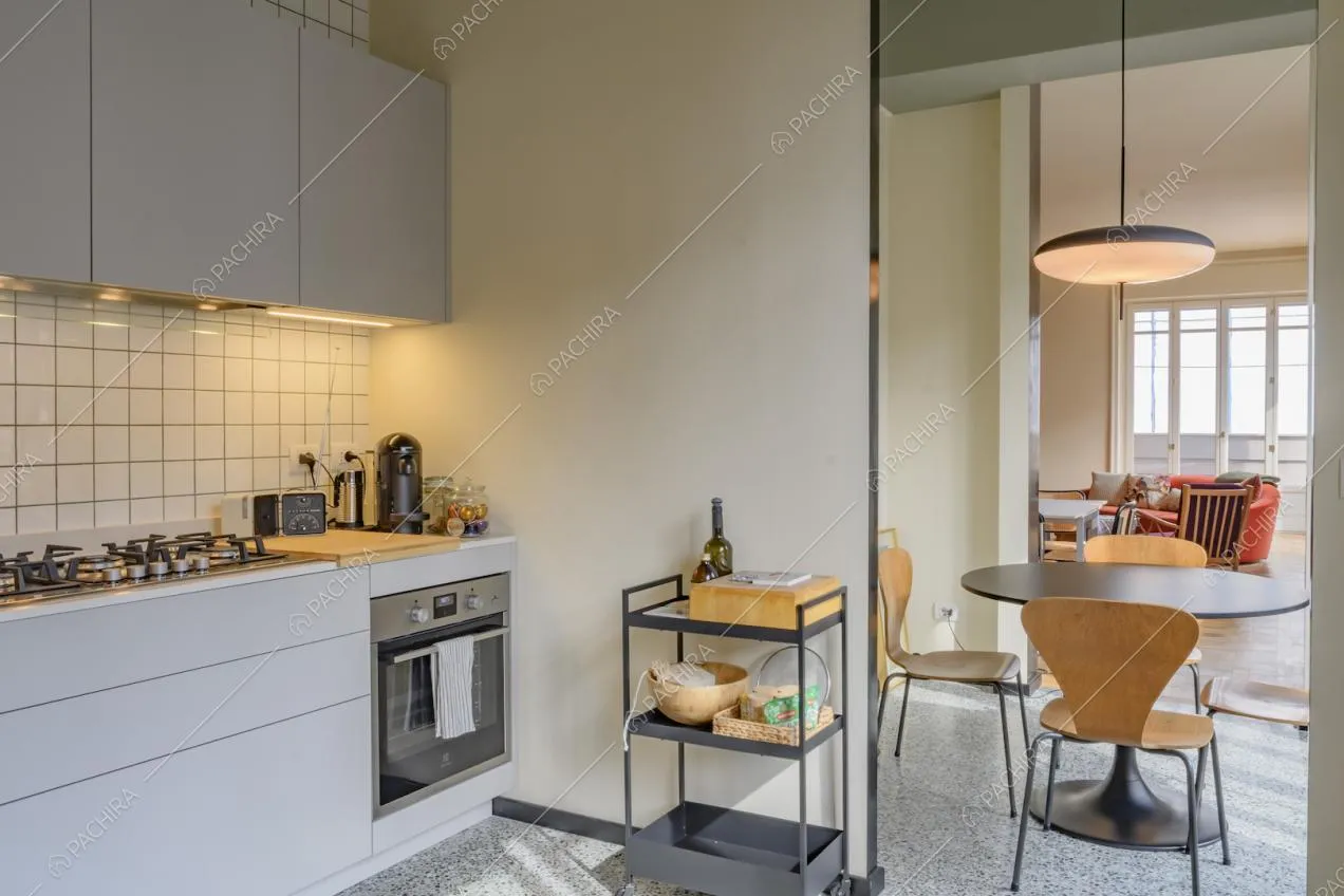 Fornelli a gas nella cucina bianca a muro con piastrelle sulla parete e vista sul tavolo da pranzo