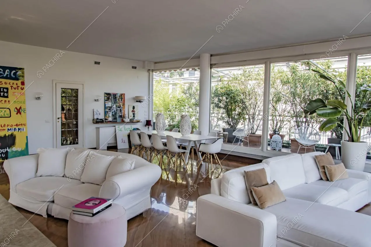 Grandi vetrate nella zona living con pavimento in parquet, divani bianchi e vista sulla terrazza