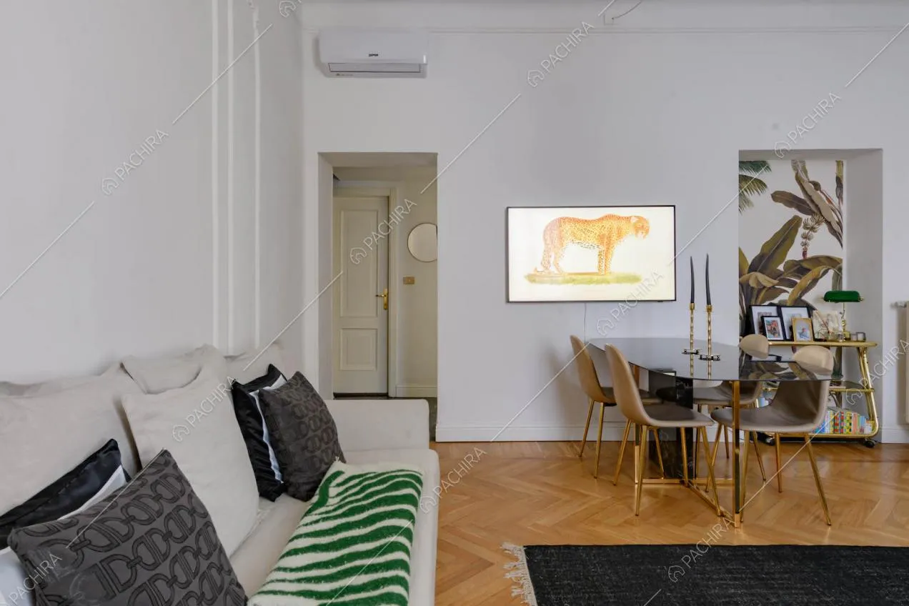 Divano bianco nel luminoso salotto con pavimento in parquet e carta da parati