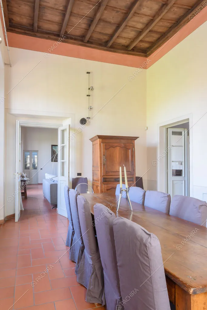Tavolo da pranzo in legno nella sala con soffitto a cassettoni e scorcio sul salotto