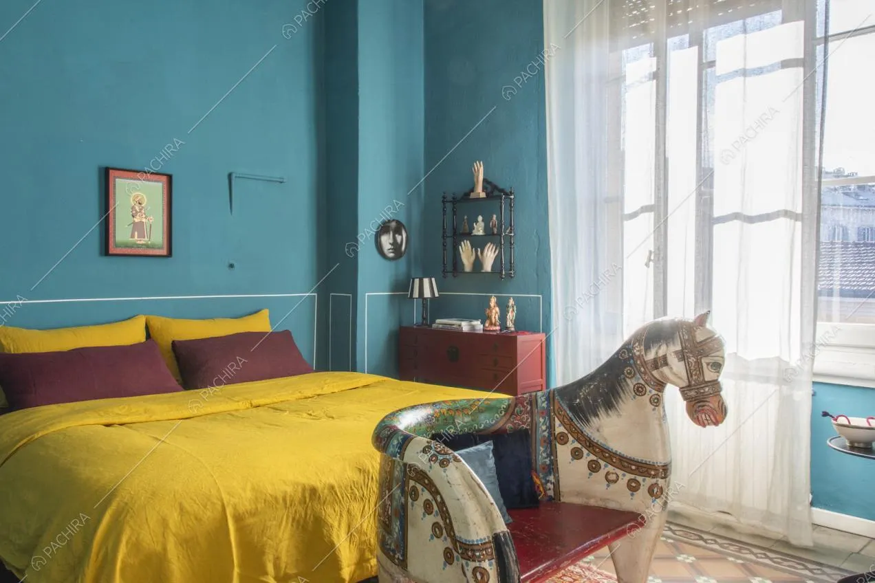Sedia a forma di cavallo e letto matrimoniale con lenzuola gialle