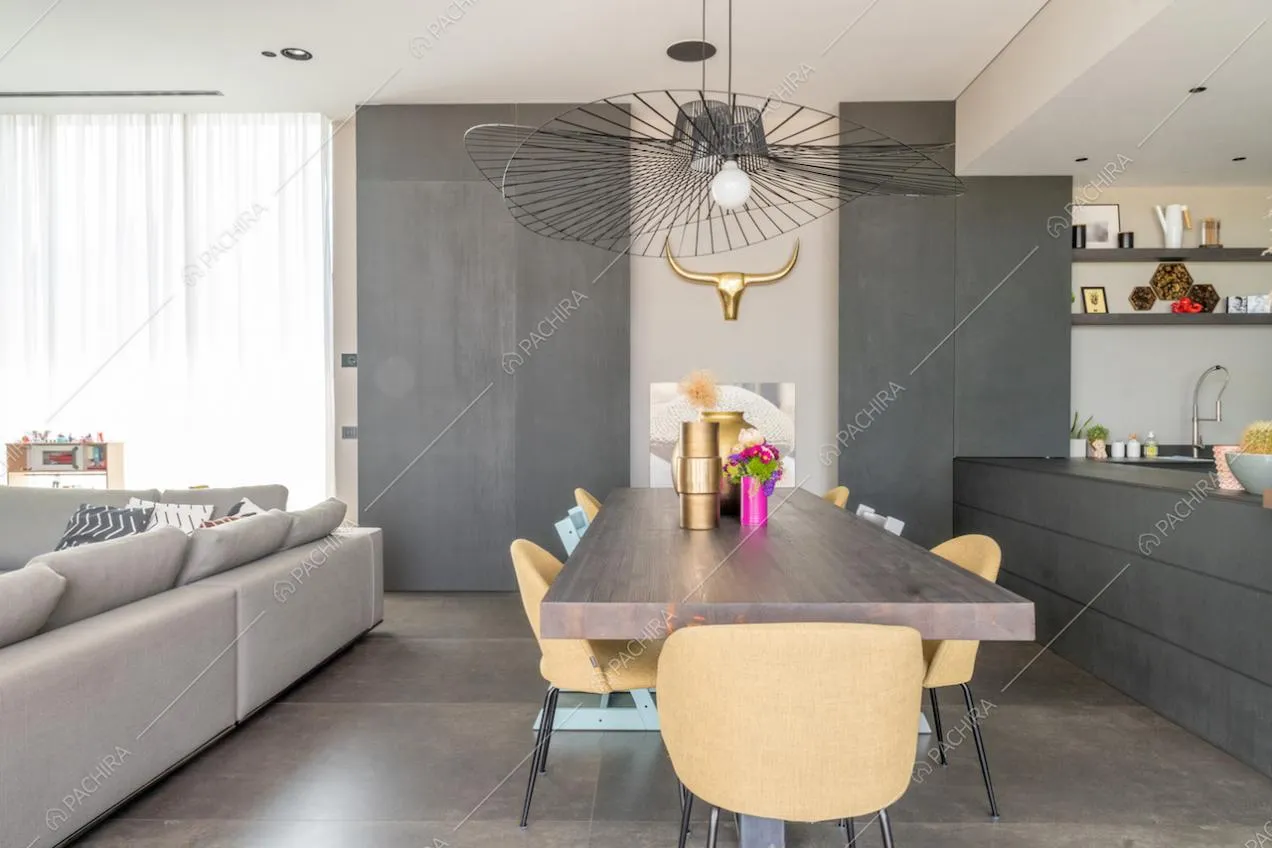 Tavolo da pranzo in legno con vista sul divano grigio angolare e sulla cucina
