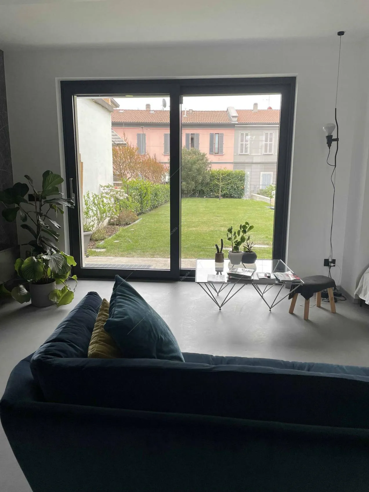 Dal divano blu in velluto vista sul giardino attraverso la porta-finestra scorrevole
