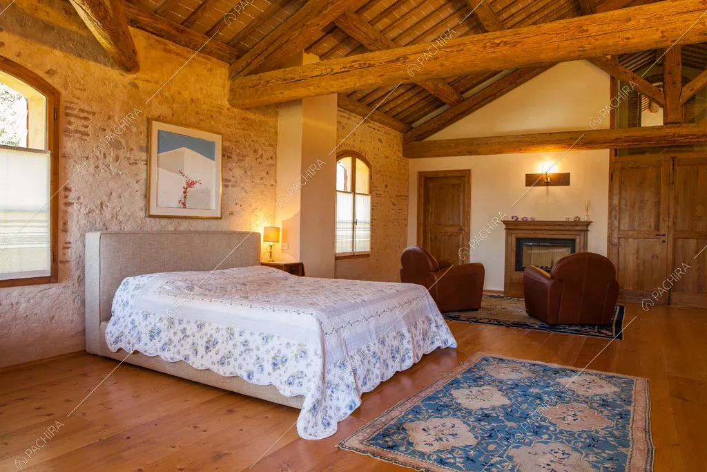 Grande camera da letto matrimoniale con pareti con mattoncini rossi a vista e parquet