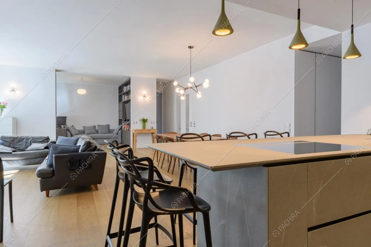 Sgabelli neri e penisola con fornelli a induzione nella cucina con pavimento in parquet