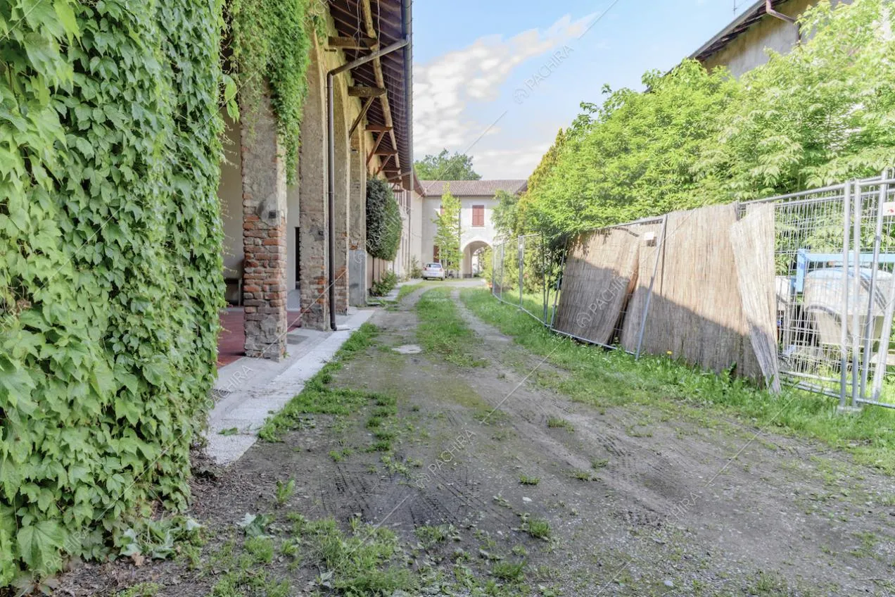 Esterni della location con colonne in mattoni rossi, edera e scorcio sull'edificio principale bianco