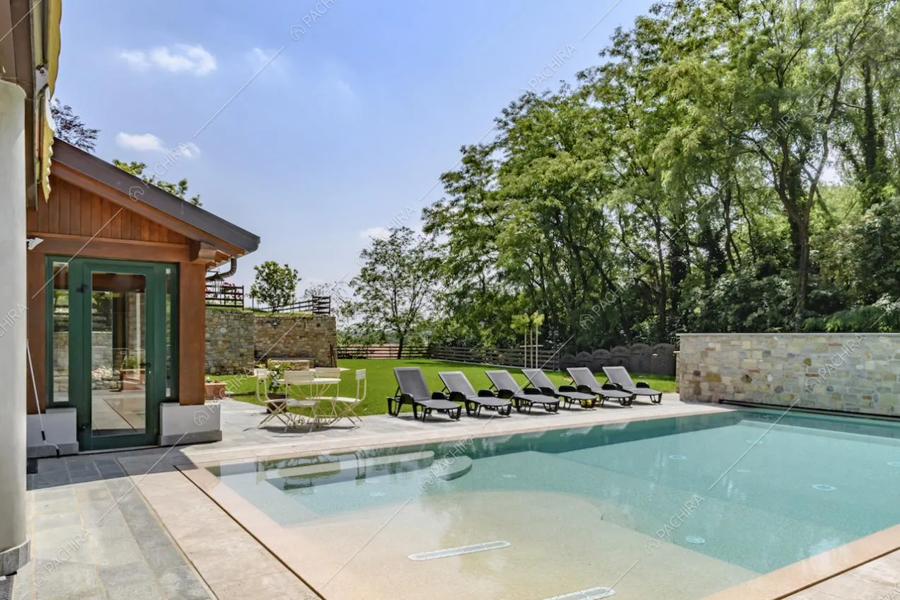 Esterni della location con veranda, tavolo da esterni, lettini e piscina nel giardino privato
