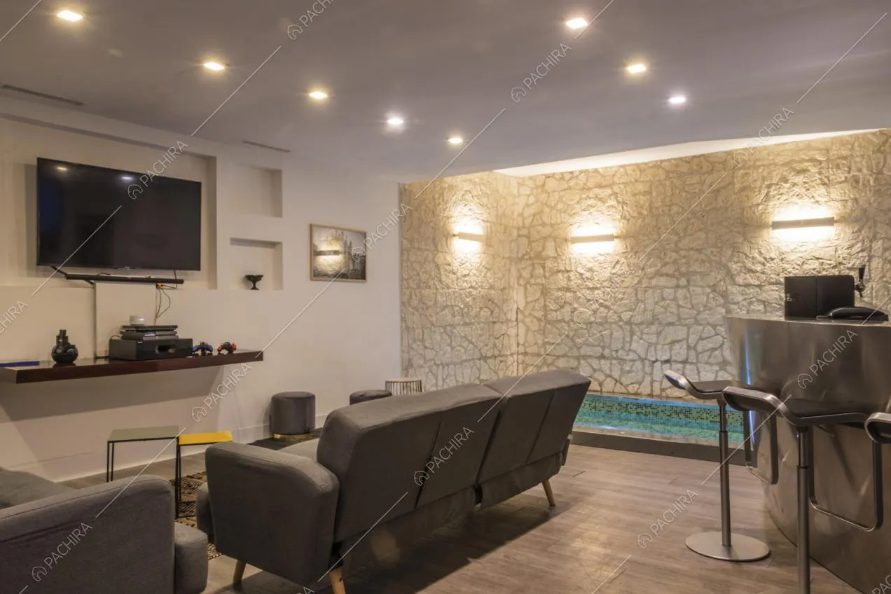Faretti sul soffitto del soggiorno, tavolini di design e pouf in velluto