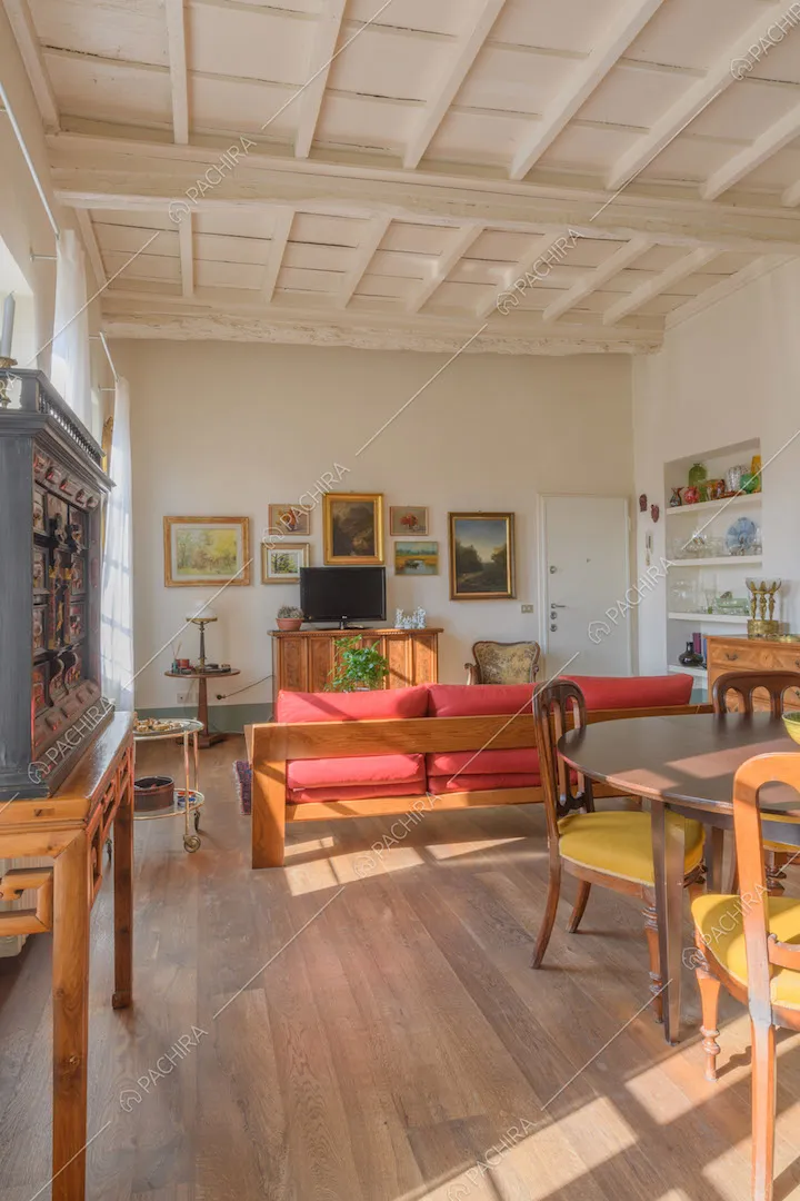 Luminosa zona living con tavolo da pranzo in legno, divano rosso e pavimento in parquet