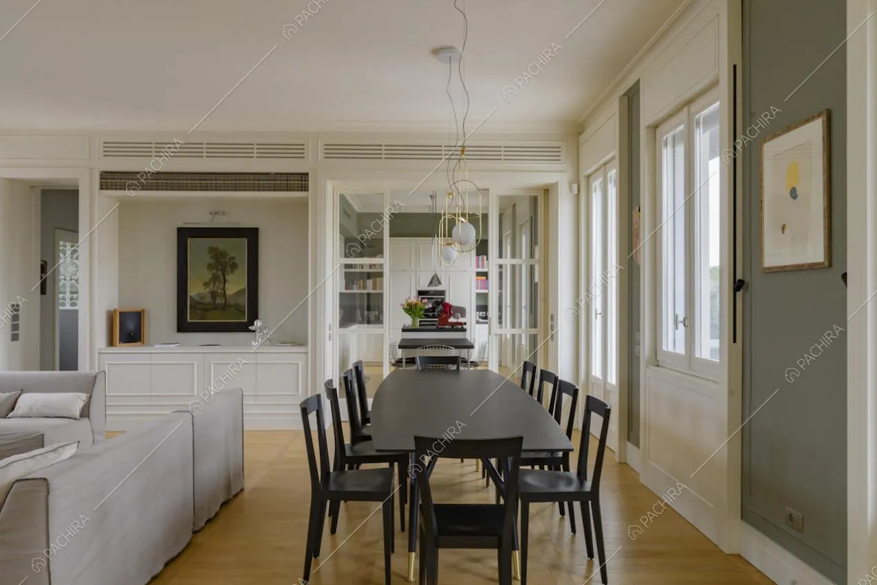 Ampia sala con divano, tavolo da pranzo nero e parquet