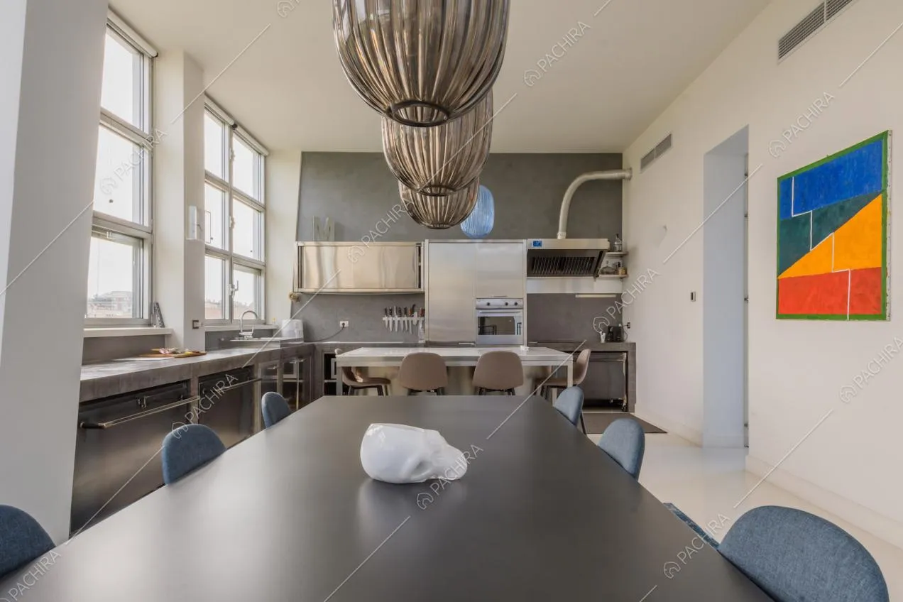 Dal tavolo da pranzo nero vista sulla cucina a isola con fornelli a induzione