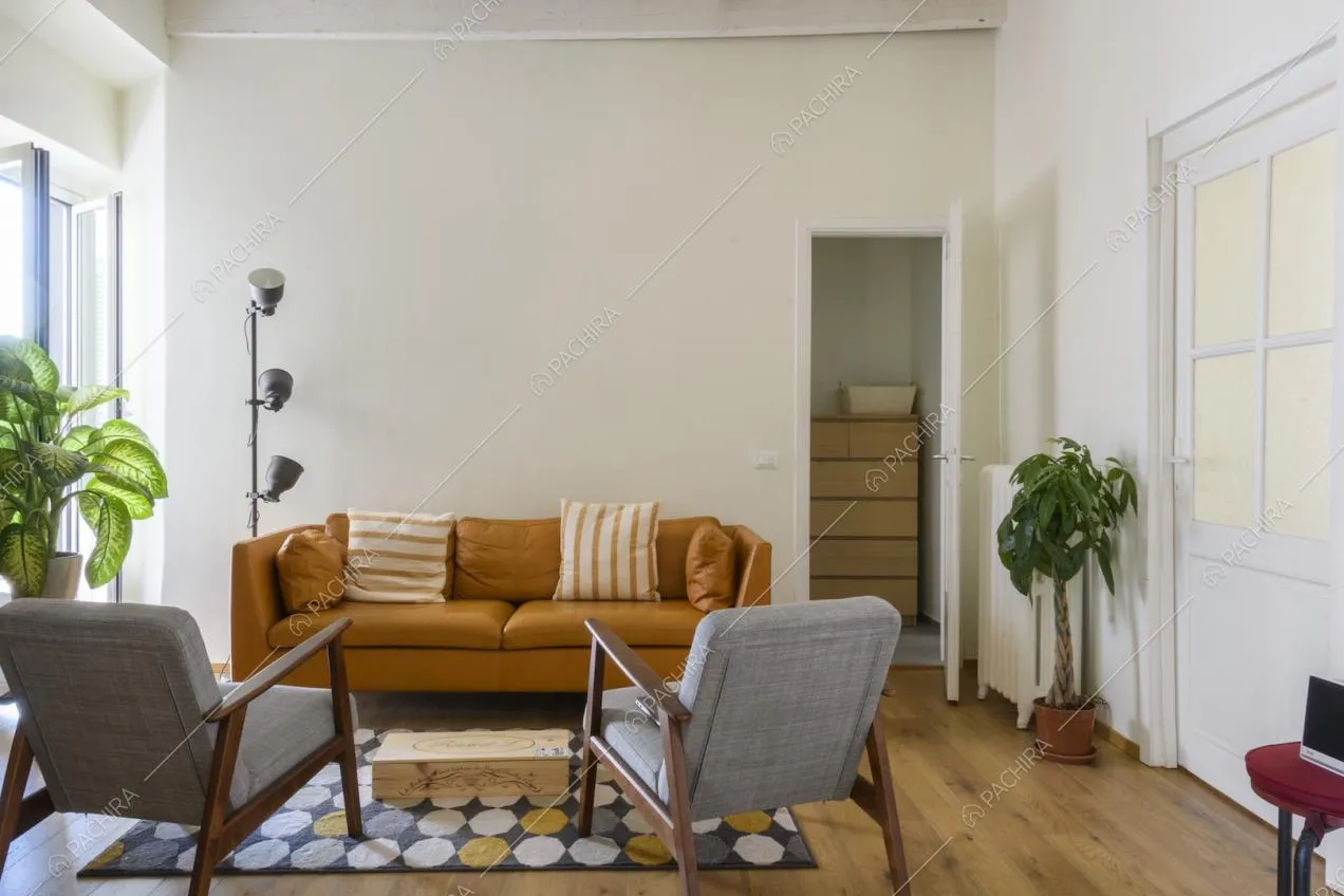 Zona conversazione con divano color senape e poltrone grigie