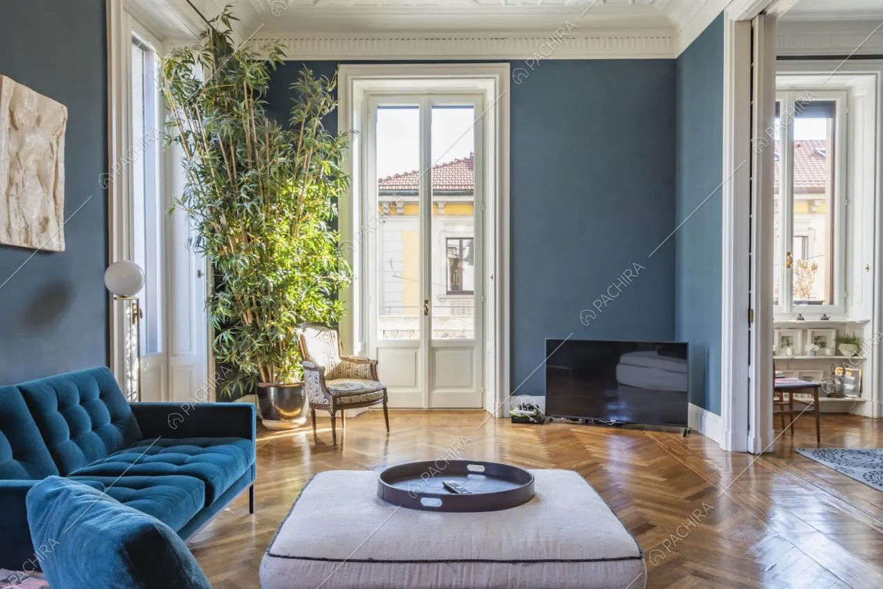 Luminoso salotto con pavimento in parquet a spina di pesce, pareti blu e boiserie sul soffitto