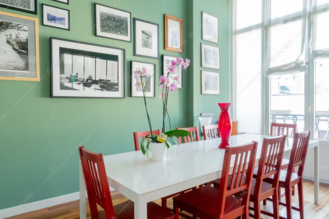 Tavolo da pranzo bianco con sedie rosse nella sala da pranzo con pavimento in parquet e pareti verdi