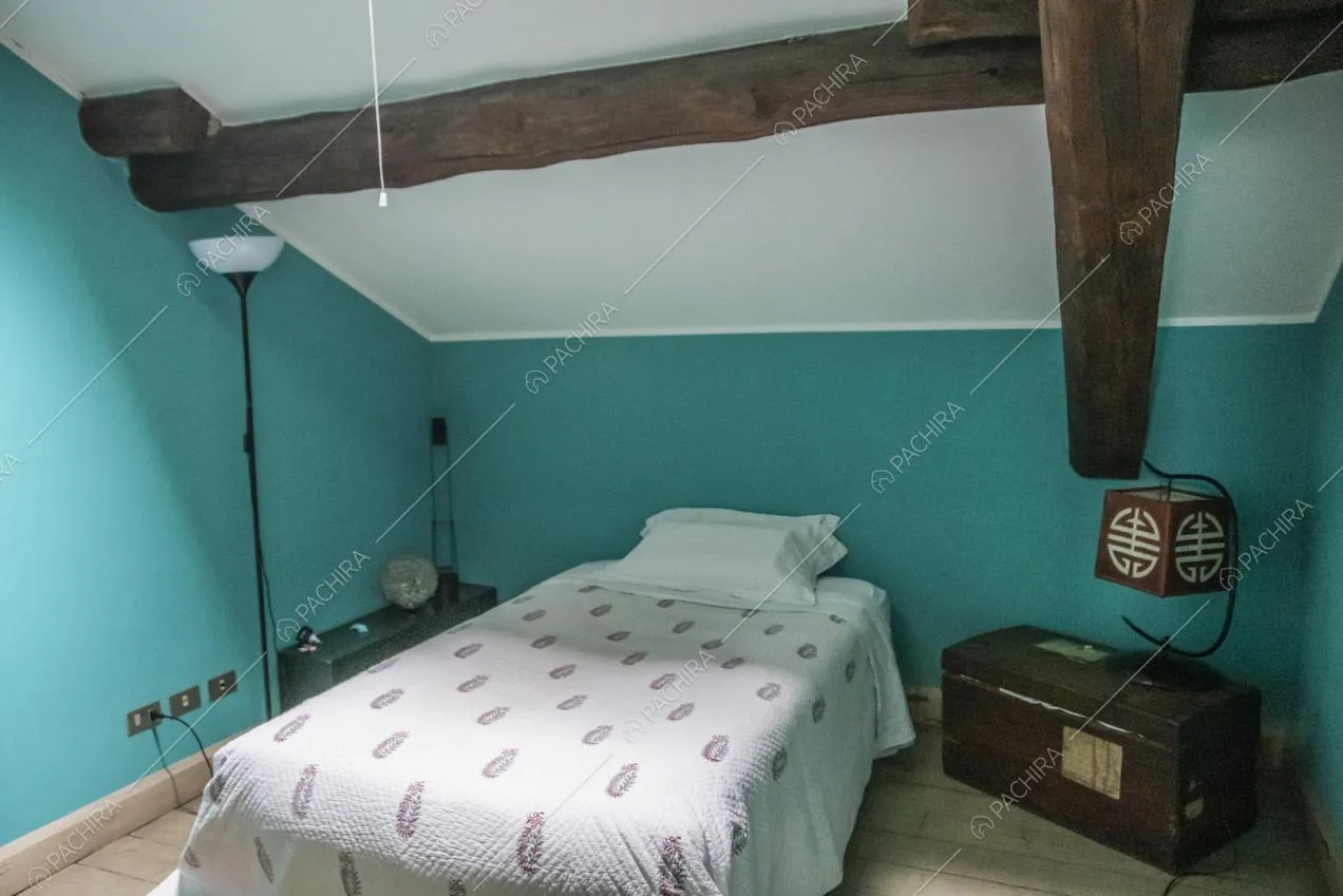 Pareti color turchese, travi in legno e letto singolo