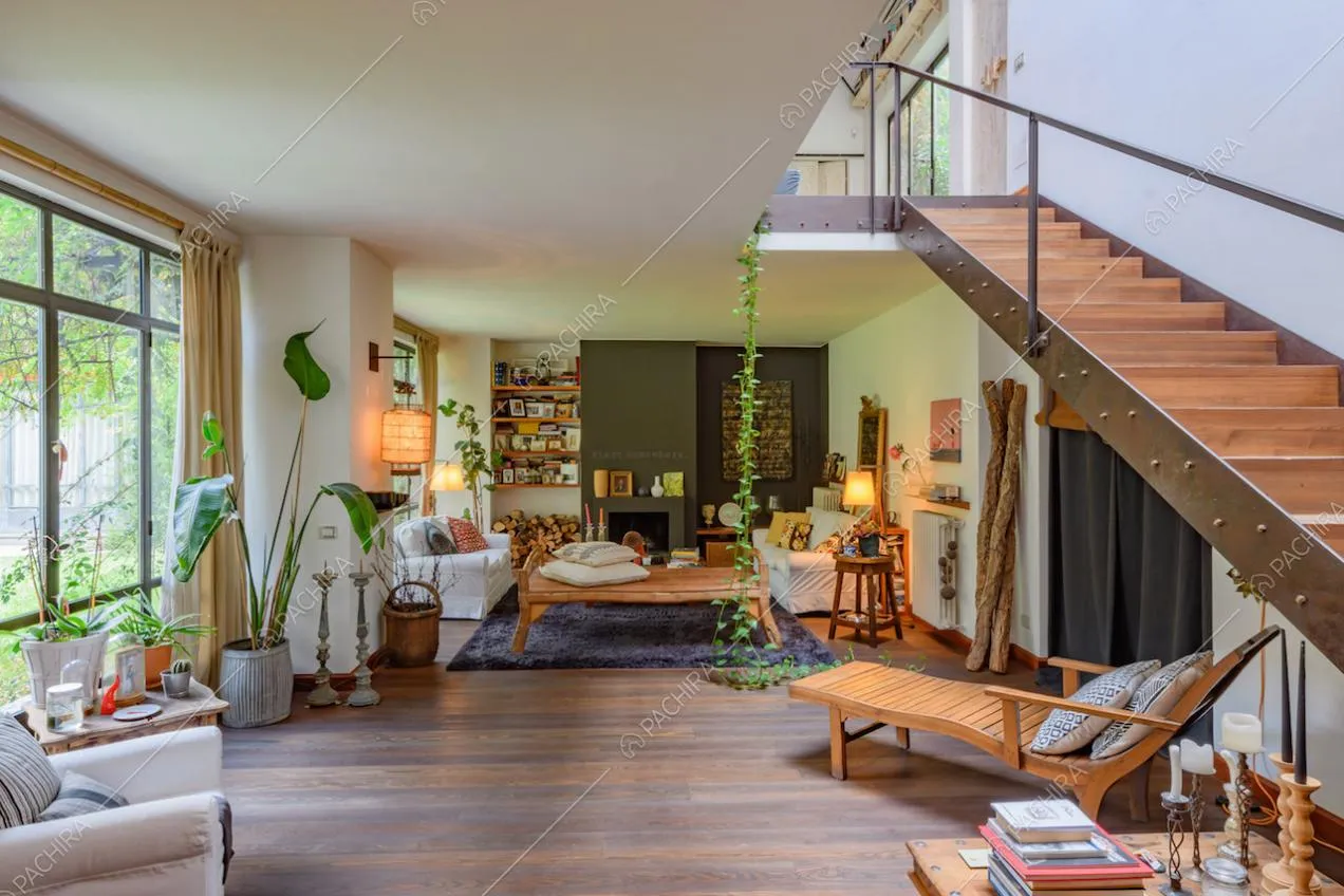 Luminoso soggiorno con grandi vetrate, scale in legno e pavimento in parquet