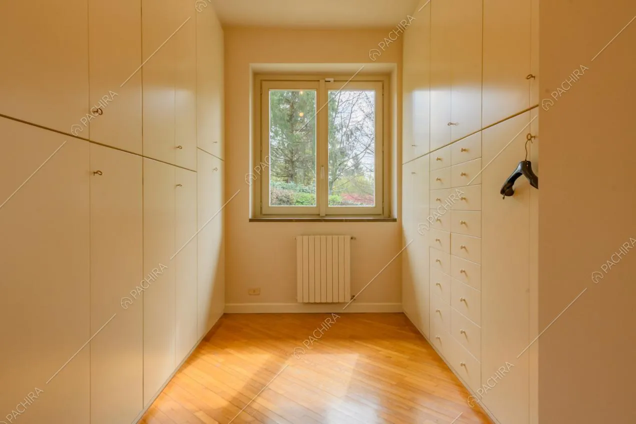 Cabina armadio con pavimento in parquet e armadi bianchi