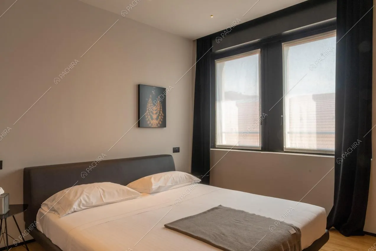 Letto matrimoniale con testata del letto nera illuminata dalle grandi vetrate