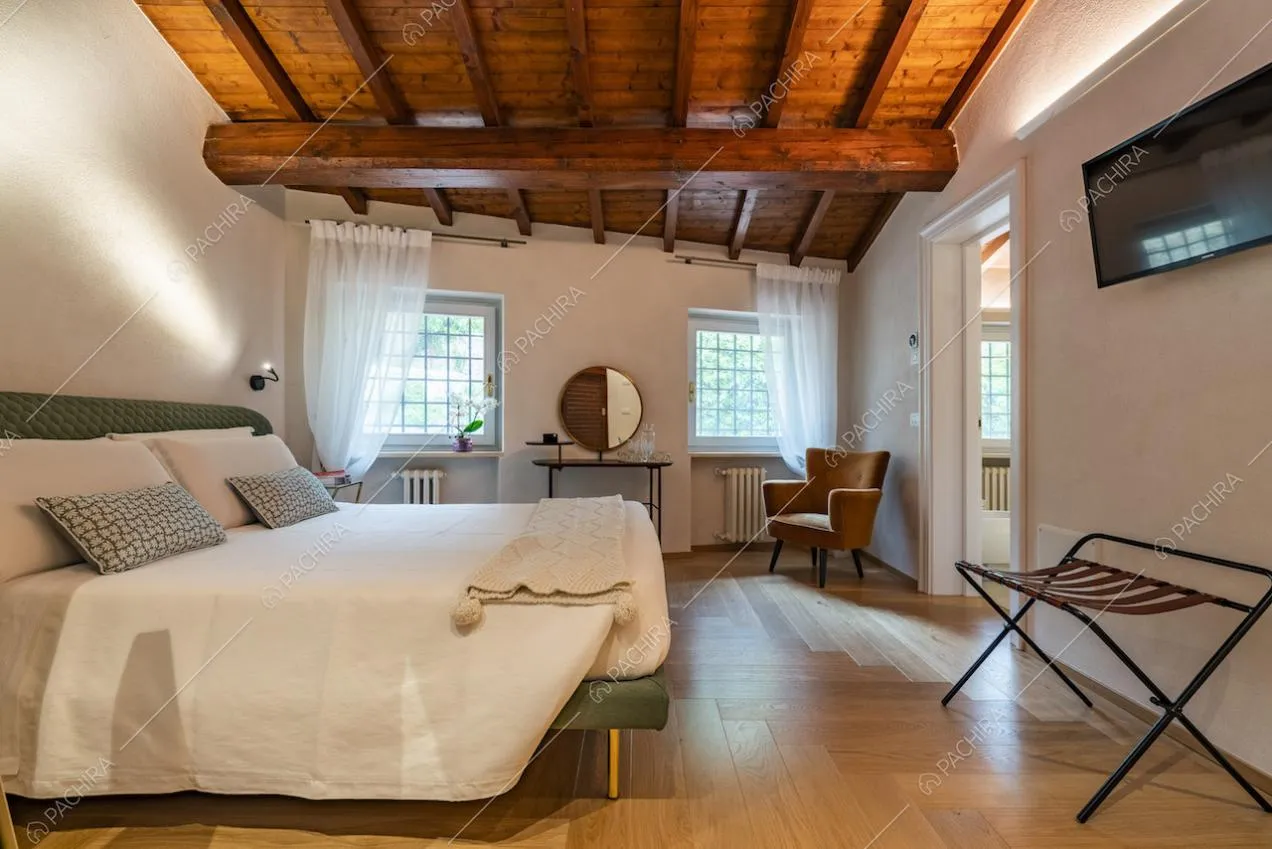 Camera da letto con due finestre e travi sul soffitto