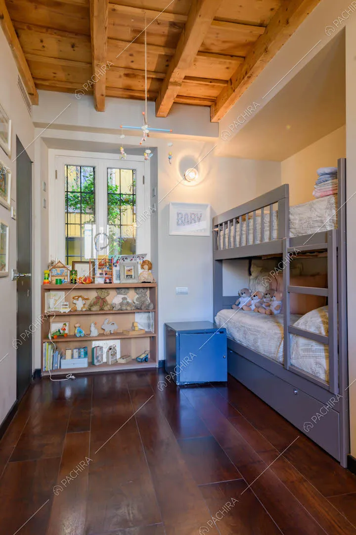 Camera da letto dei bambini con letto a castello e soffitto con travi in legno a vista