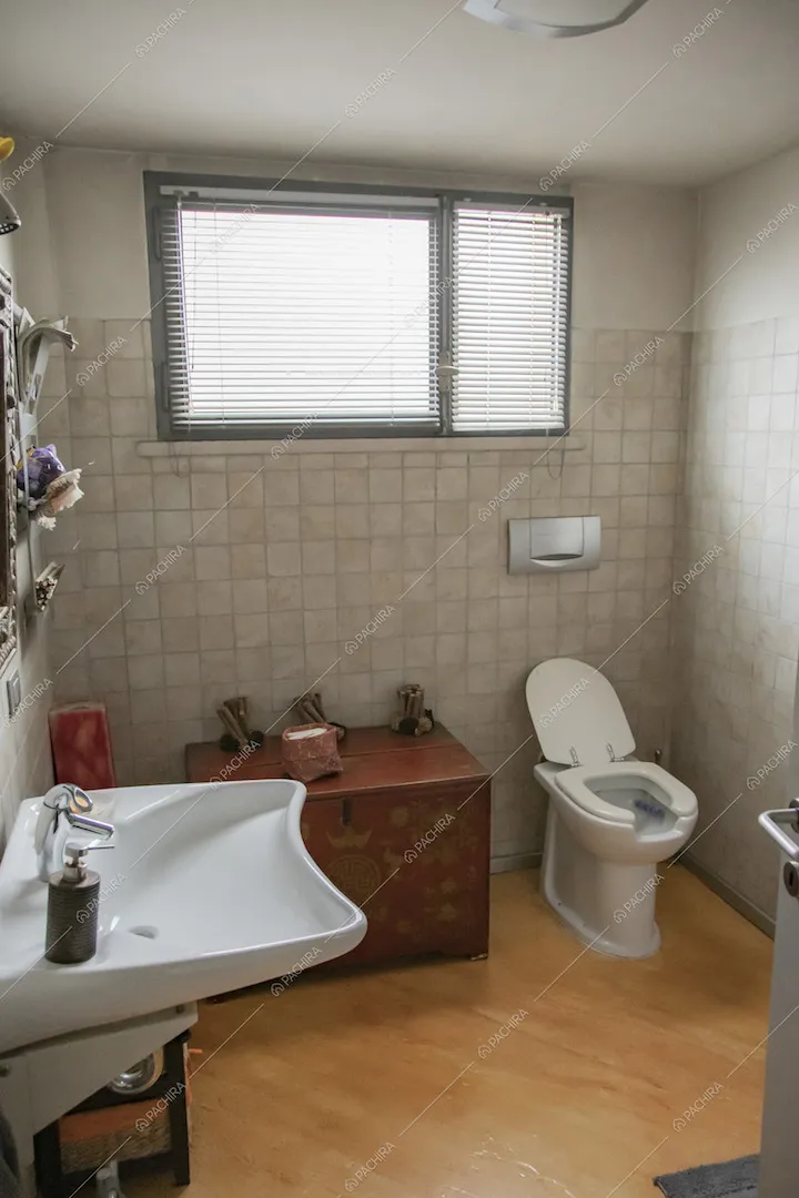 Bagno con pavimento in parquet, pistrelle alle pareti bianche e finestra