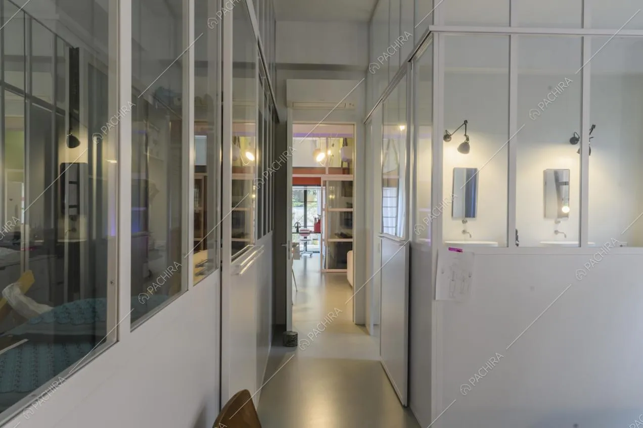 Corridoio con vetrate industriali bianche e vista su camera da letto 