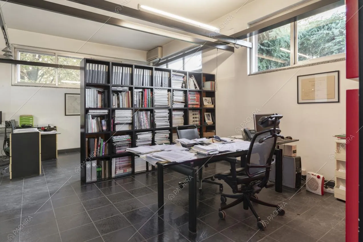 Grande scaffale con libri e faldoni di fronte alla scrivania