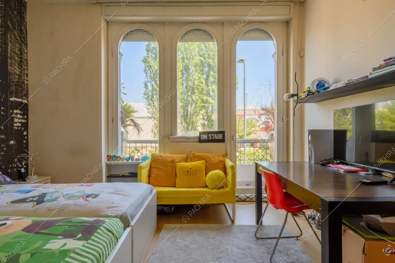 Luminosa camera da letto con pareti bianche e pavimento in parquet