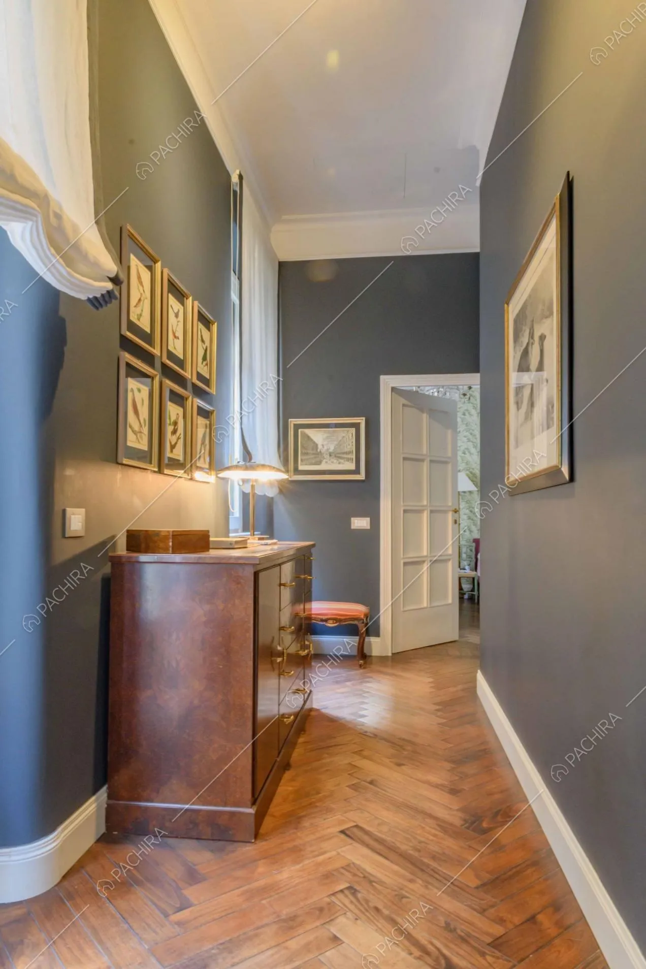Dal luminoso corridoio dalle pareti blu, scorcio sulla camera da letto con carta da parati verde