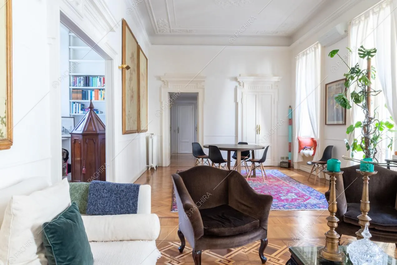 Dal divano bianco vista sulla sala con tavolo da pranzo e sulla libreria