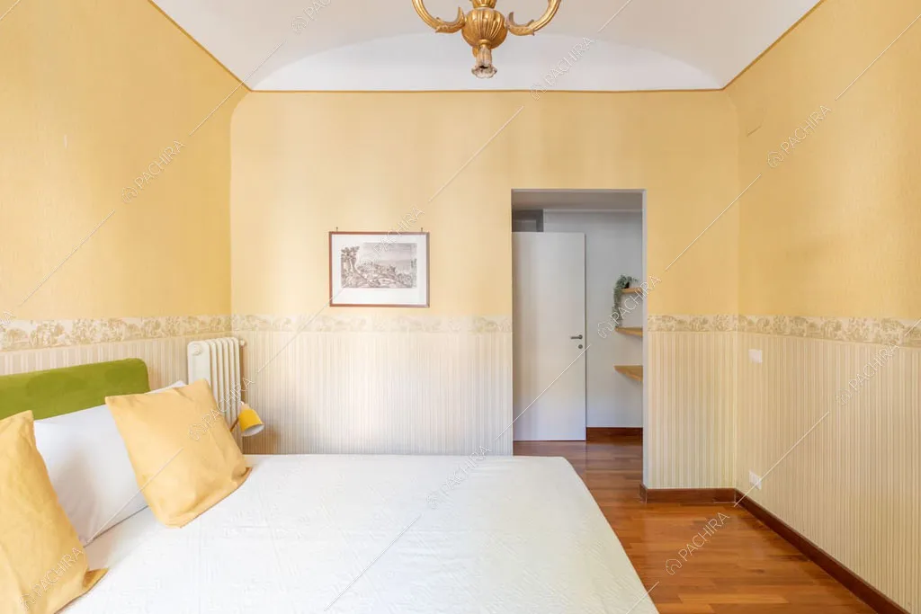 Camera da letto matrimoniale con pareti gialle dell'appartamento Crescione, location in stile contemporaneo a Roma