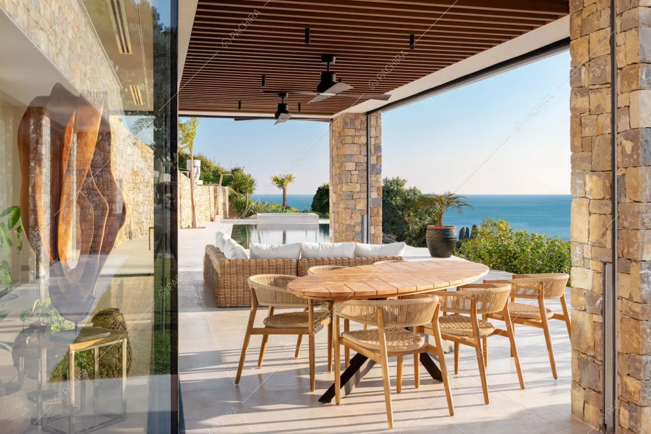 Tavolo da pranzo in legno e divano nella veranda sulla terrazza vista mare