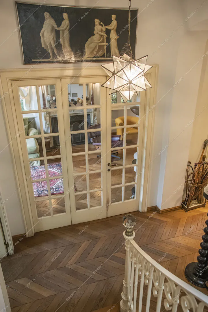 Dalle scale vista sull'atrio con pavimento in parquet a spina di pesce tramite la porta a vetri