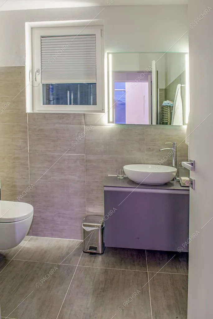 Bagno con mobile sospeso e piastrelle grigie