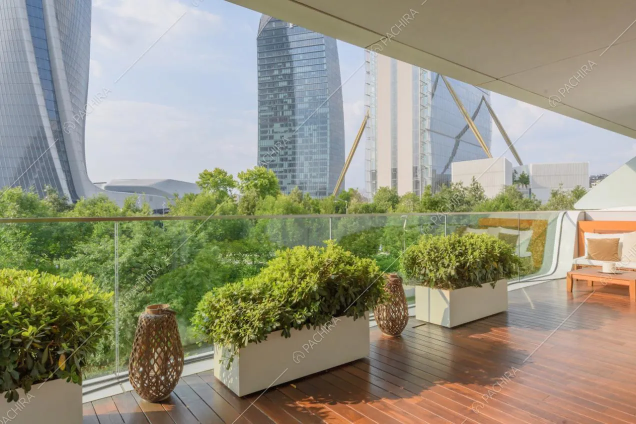Parapetto in vetro sulla terrazza con pavimentazione in parquet e vista sul parco