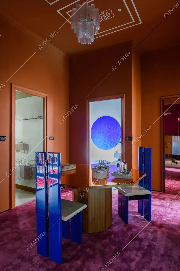 Vista sul tavolo arancione ottagonale nell'atrio con moquette fucsia e vista sulle altre stanze