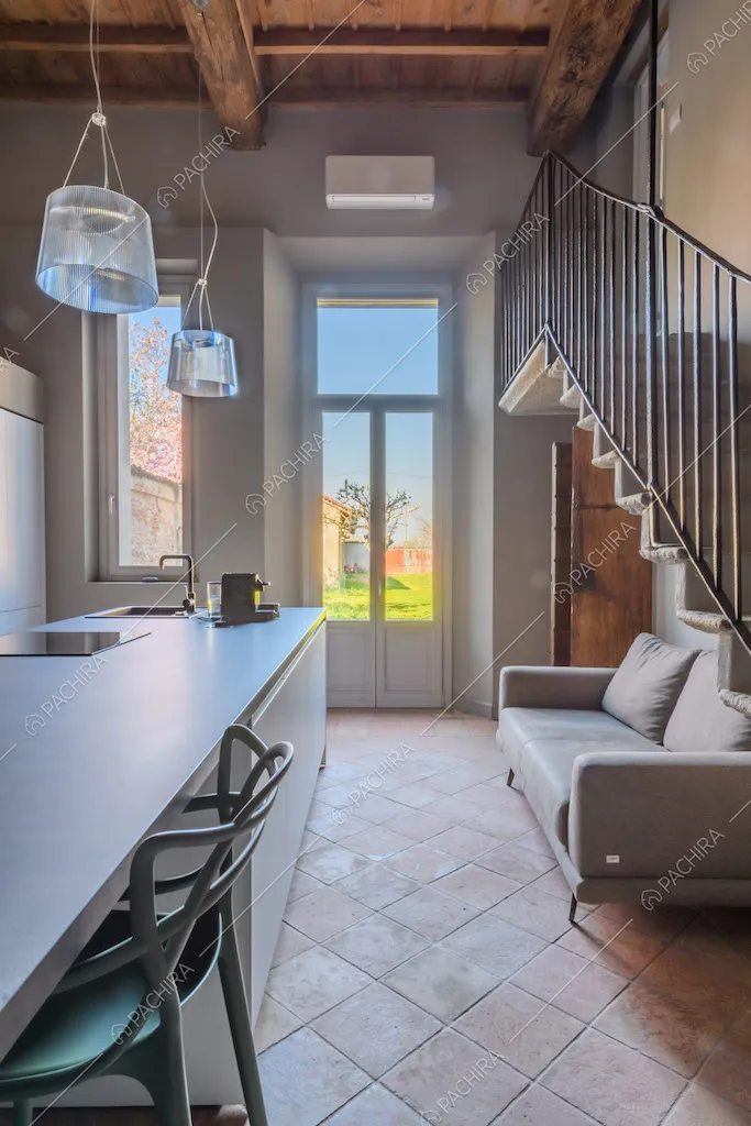Luminosa cucina con pavimento in cotto, porta-finestra e soffitto in travi in legno a vista