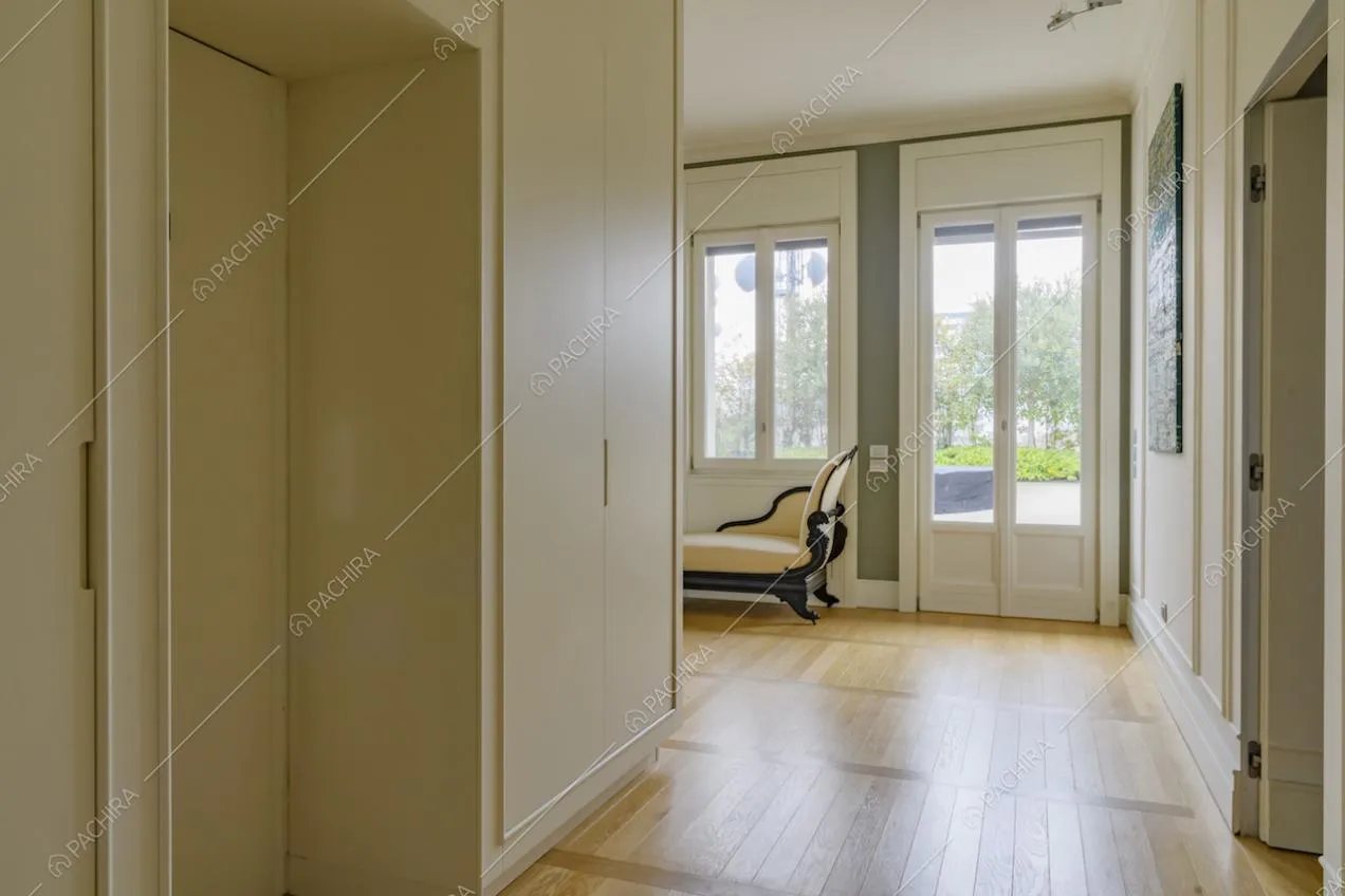 Corridoio con pavimento in parquet, porta-finestra e divano in stile classico
